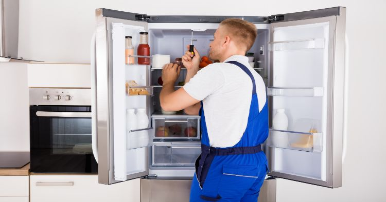 man repairing inside of a refrigerator