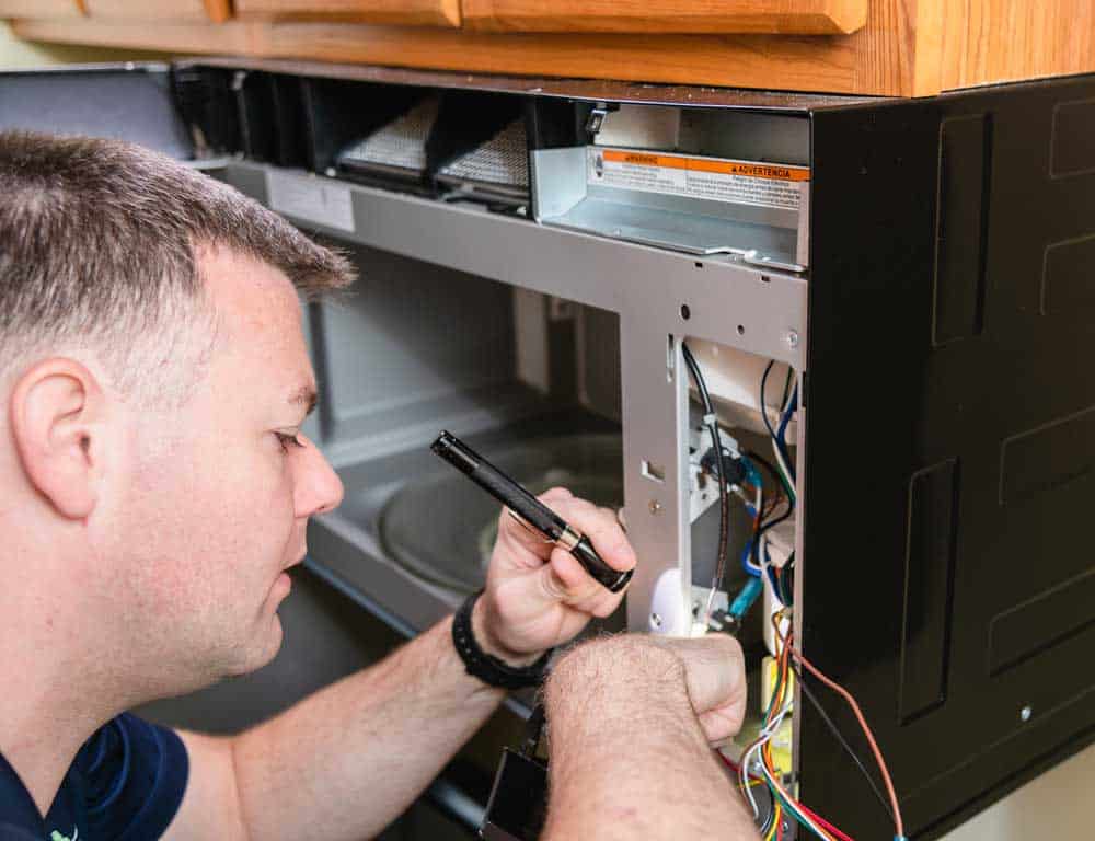 man repairing microwave
