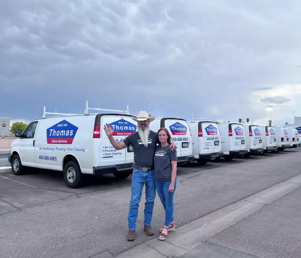 Thomas Home Services owner, Will Thomas, and his wife, Marci, in Chandler, AZ standing next to their branded service vans.